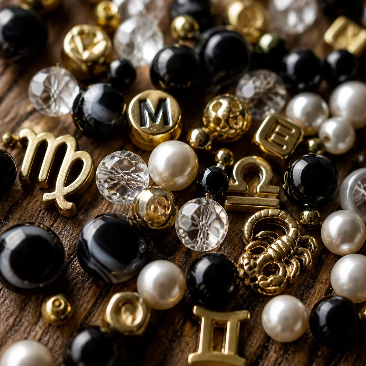Close-up of black, pearl, crystal and gold letter beads on wood