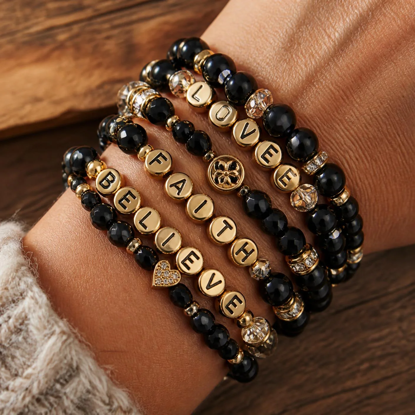A stack of handmade black, gold and crystal beaded bracelets on a wrist